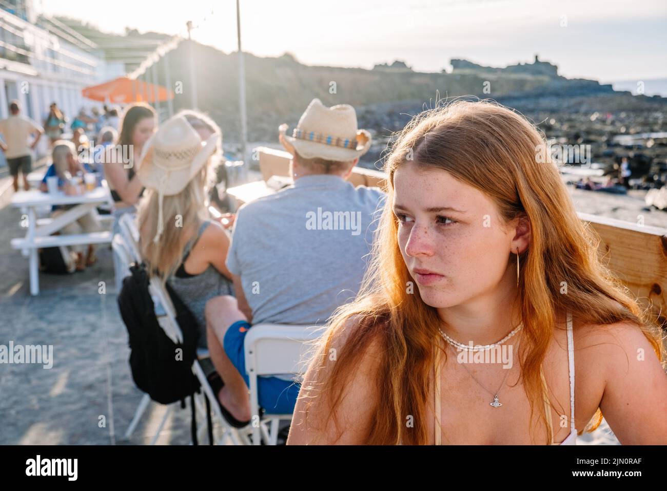 Eine Nahaufnahme einer schönen jungen Ingwerfrau mit Sommersprossen in einem Straßencafé. St Ives, Cornwall, Großbritannien. Stockfoto