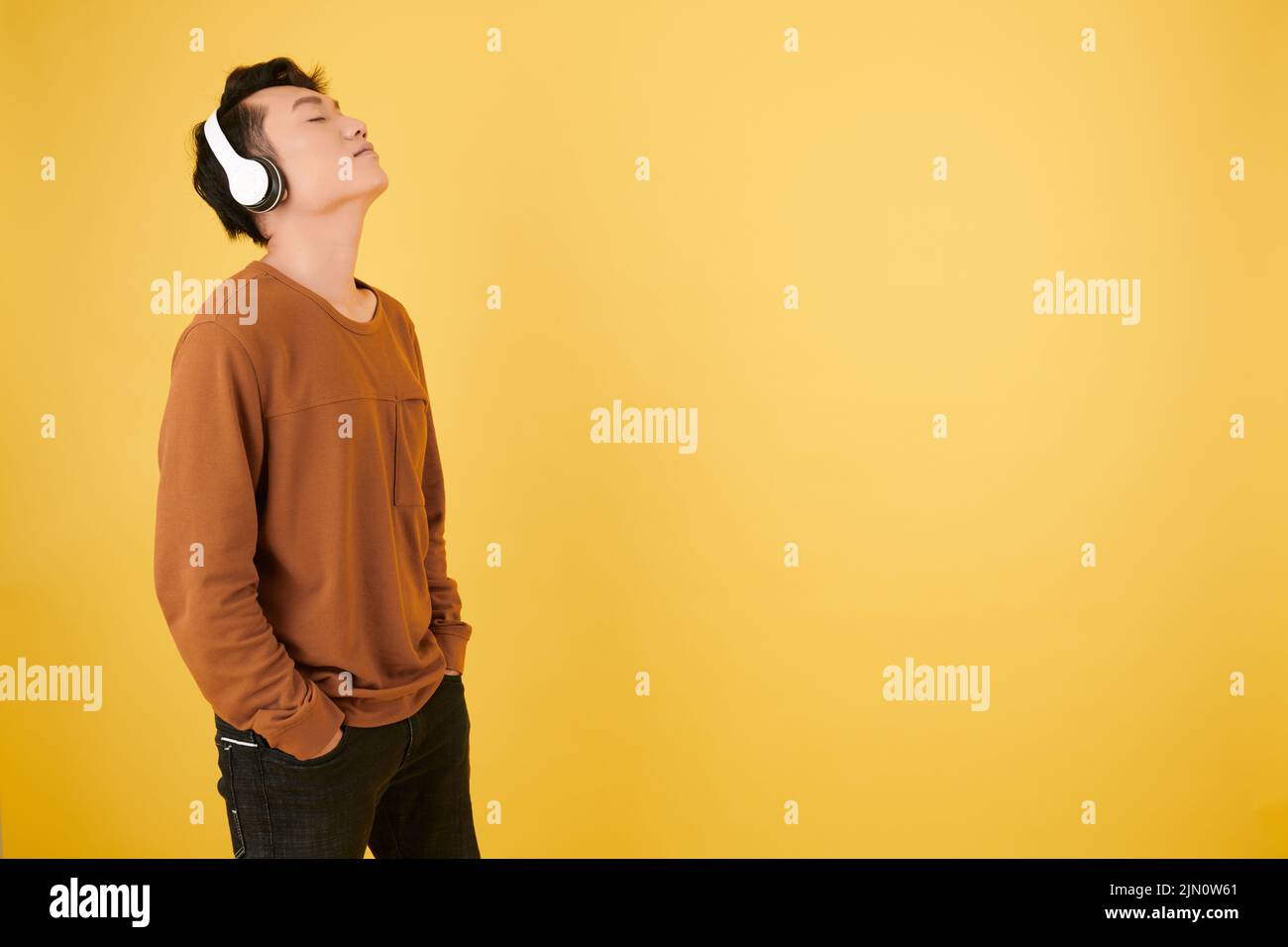 Der junge Mann lehnte sich den Kopf zurück, als er sein Lieblingslied über Kopfhörer genießen konnte Stockfoto