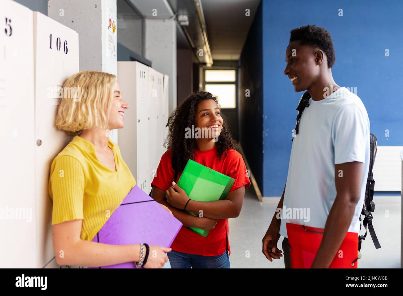 Multirassische Gruppe von Studentenfreunden, die sich auf dem Schulflur unterhalten Stockfoto