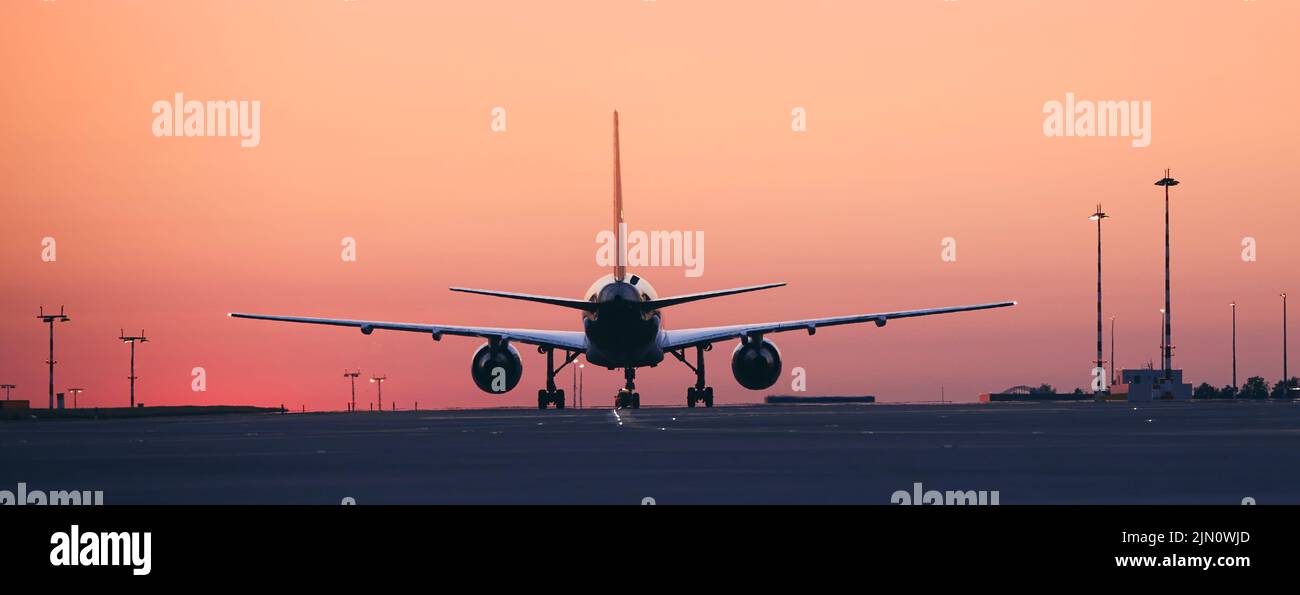 Rückansicht des Flugzeugs, das zum Start auf die Startbahn rollt. Verkehr am Flughafen in der Morgendämmerung. Stockfoto
