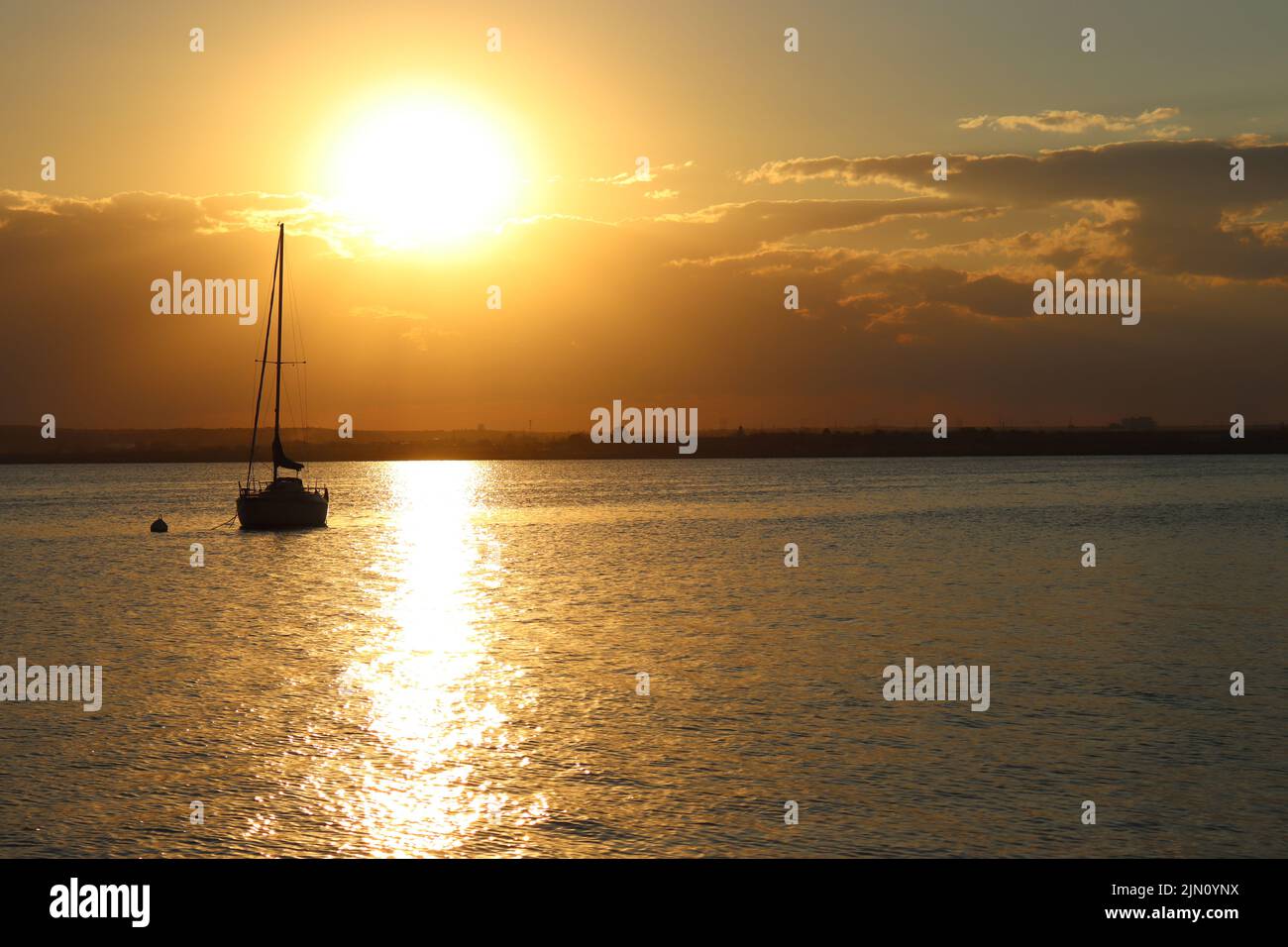 Lebhafter Sonnenuntergang, der sich in den Gewässern Italiens widerspiegelt, während das Fischerboot friedlich vorbeifährt Stockfoto