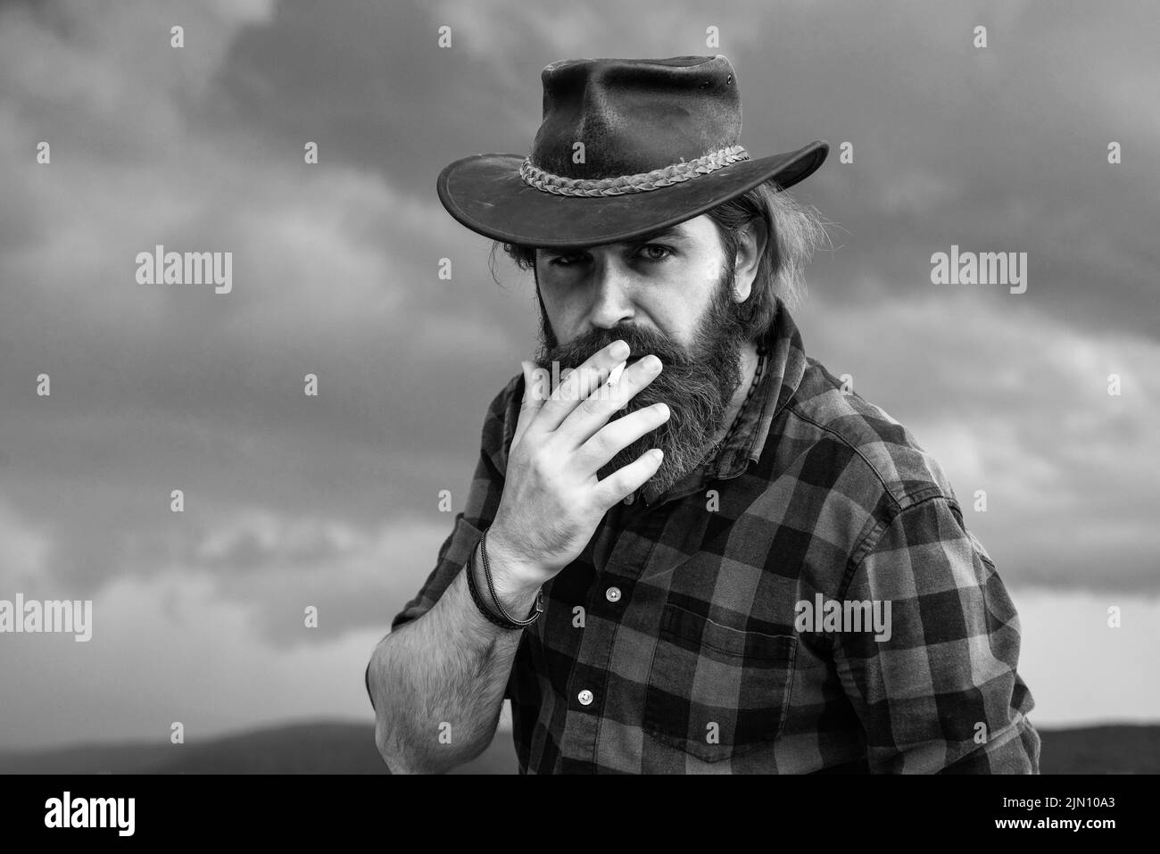 Reifer Mann mit Bart trägt Cowboyhut und raucht Zigarette, Westen Stockfoto
