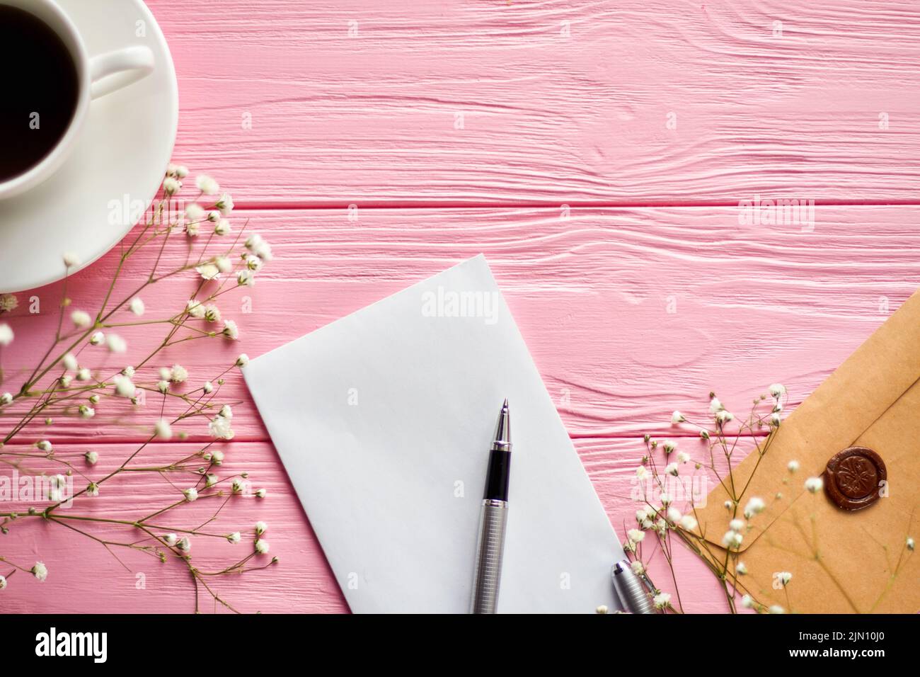 Draufsicht leerer Notizblock mit Stift und Kaffeetasse. Rosafarbener Holzschreibtisch mit Platz für Kopien. Stockfoto