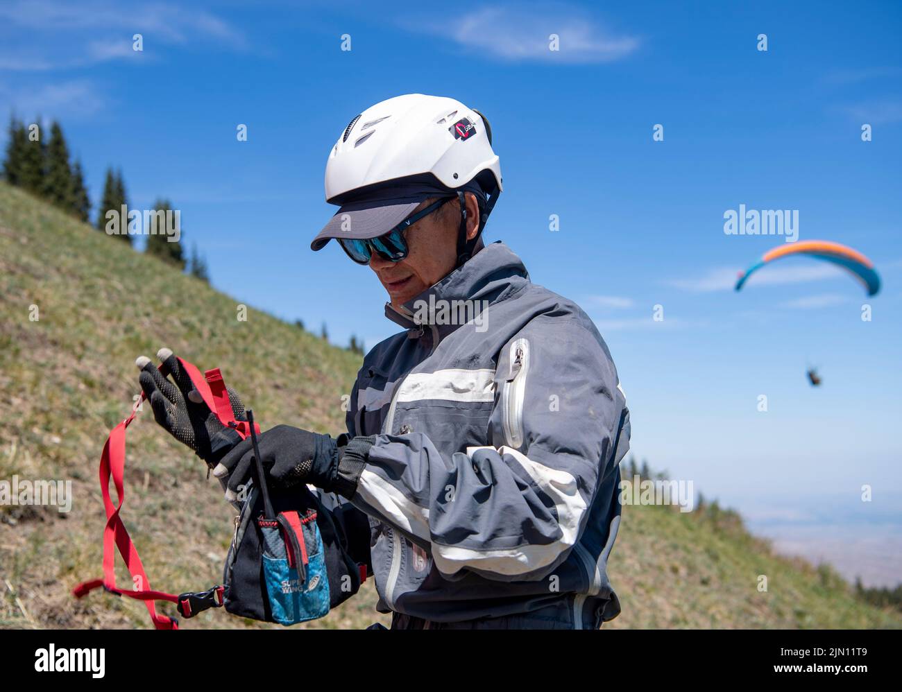 (220808) -- XINJIANG, 8. August 2022 (Xinhua) -- Chen Ruifeng überprüft sein Radio vor dem Start im Bezirk Jimsar, nordwestlich der Autonomen Region Xinjiang Uygur in China, 21. Mai 2022. Der 52-jährige Chen Ruifeng, der in Xinjiang geboren wurde, ist ein Paragliding-Amateur. Er sagt, dass er sich wie mit seinen eigenen Flügeln fühlt, wenn der Gleitschirm geöffnet wird. Im Jahr 2016 begann Chen Ruifeng, Gleitschirmfliegen zu üben. Später trat er einem lokalen Verein bei und erhielt nach dem Training seine Flugbescheinigung. Als Outdoor-Enthusiast engagiert er sich auch für Trailrunning, Bergsteigen und Eisklettern. Seiner Meinung nach das einzigartige Gelände von Xinj Stockfoto