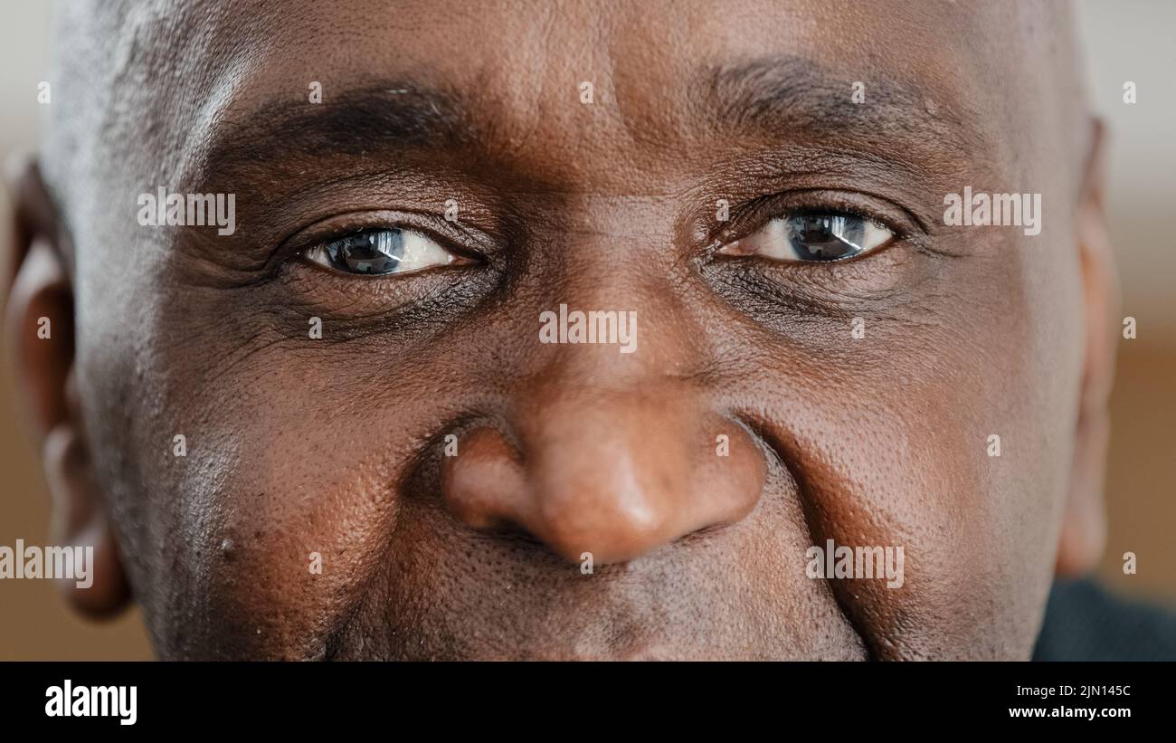 Nahaufnahme Teil männlich Gesicht glücklich älteren afroamerikanischen Mann lächelt mit freundlichen dunklen schwarzen Augen. Gutaussehende ältere Bürger mit Falten suchen Stockfoto