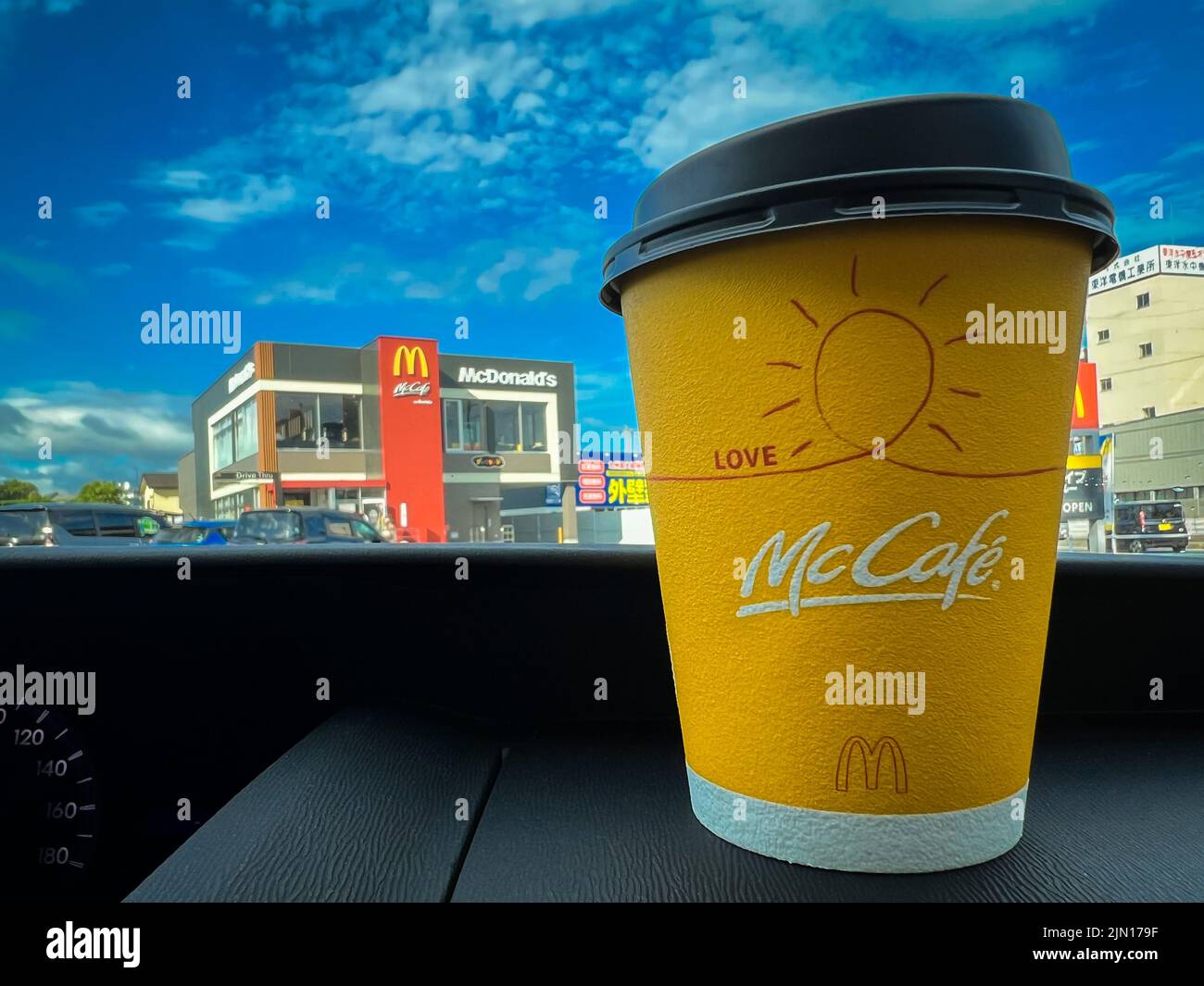 Gelbe Tasse McCafe Japan Kaffee auf dem Armaturenbrett eines Autos, das beim McDonalds Drive-Service gekauft wurde. Stockfoto