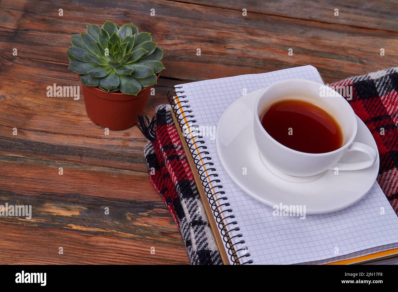 Weiße Teetasse von oben auf dem Notizblock. Brauner Holzschreibtisch. Stockfoto