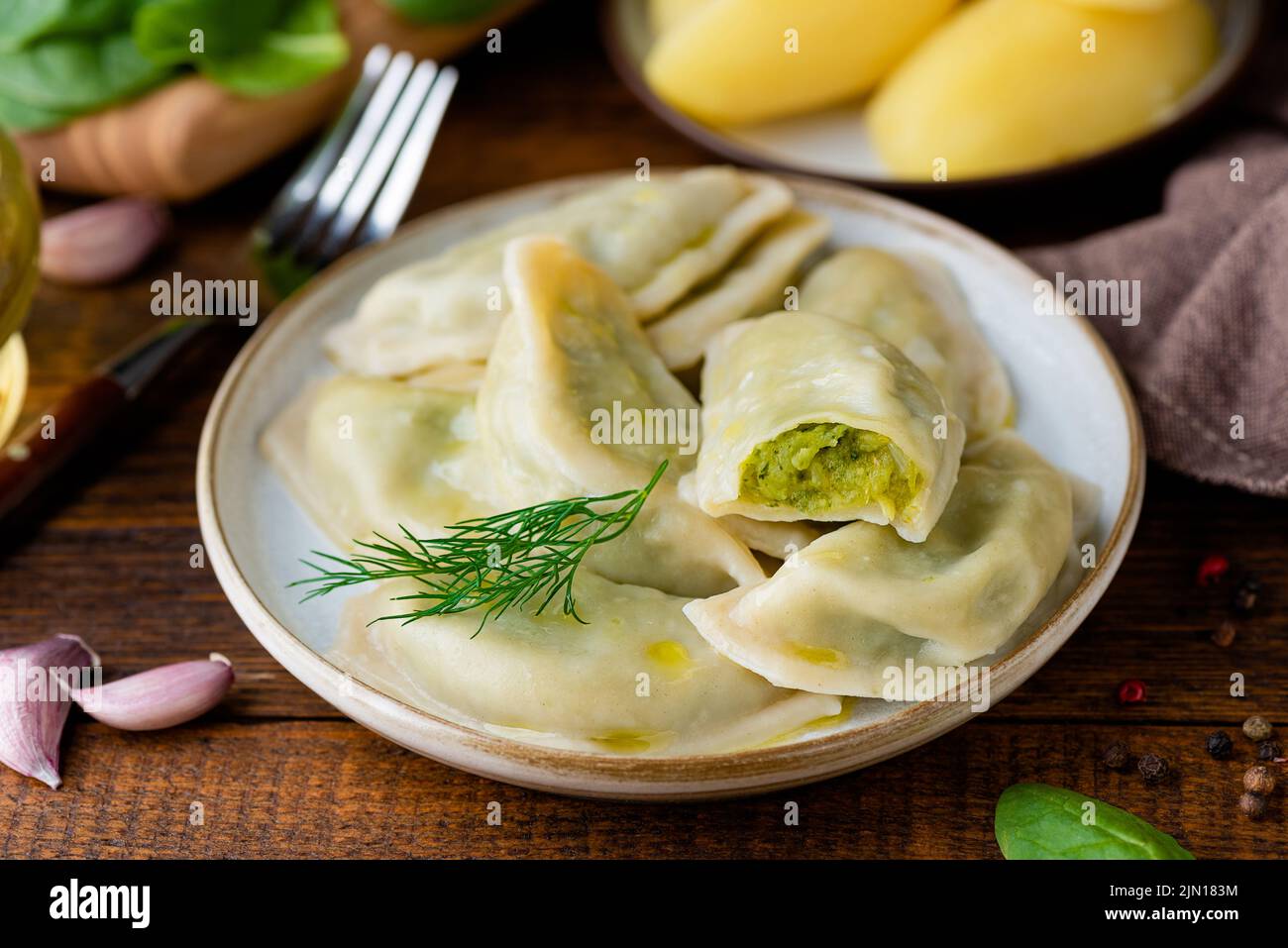 Ukrainische oder polnische Knödel, mit Kartoffeln und Spinatbrei gefüllte Pierogi, serviert mit Olivenöl, Nahaufnahme Stockfoto