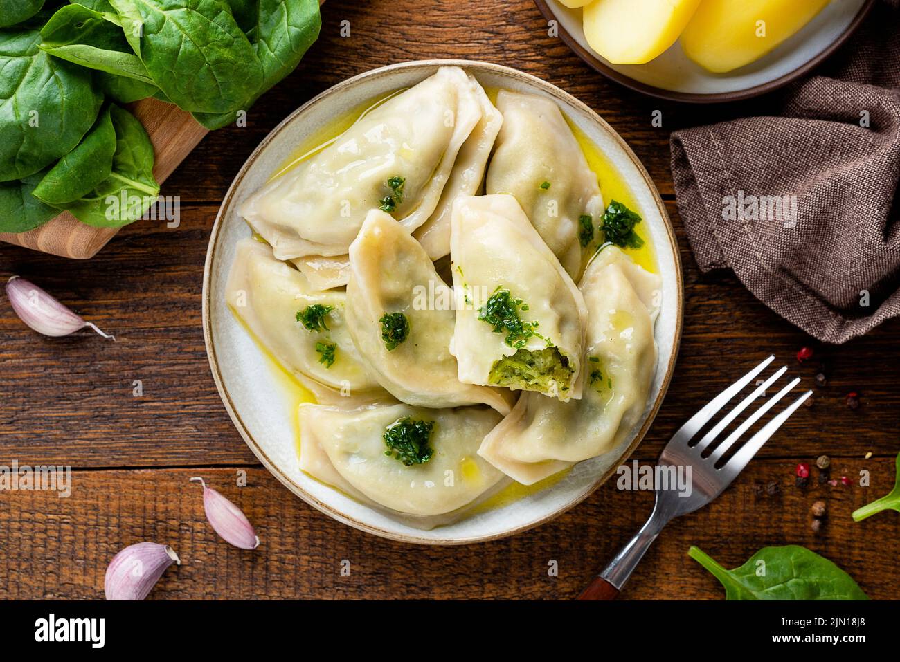 Spinatkartoffeln gefüllte Knödel oder Pierogi, ukrainische, polnische Küche Essen. Draufsicht, Holztisch Hintergrund Stockfoto