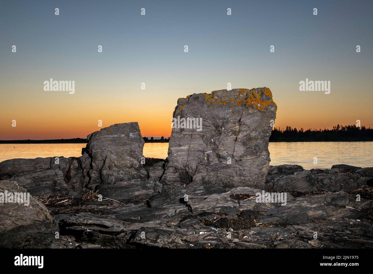 6. Juli 2022. 8:22 Uhr. Zwei Felsen bei Sonnenuntergang. Barnes Island. Casco Bay, Maine. Stockfoto