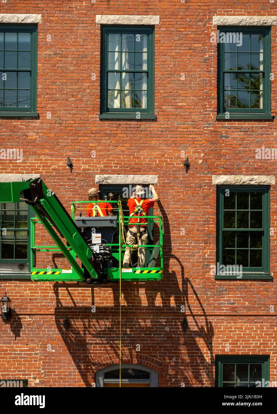 Bauarbeiter installieren neue Fenster an einem Mühlengebäude in der Innenstadt von Bideford Maine Stockfoto