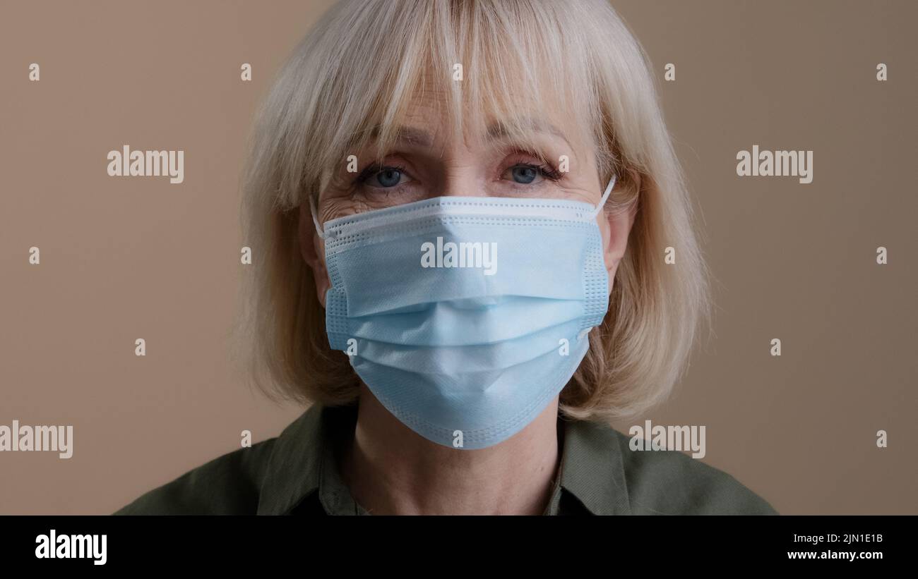 Nahaufnahme weibliche Porträt drinnen ältere kaukasische gesunde alte Frau 60s Patienten Dame zu Hause im Studio drinnen in der Klinik Abnehmen medizinische Maske Stockfoto