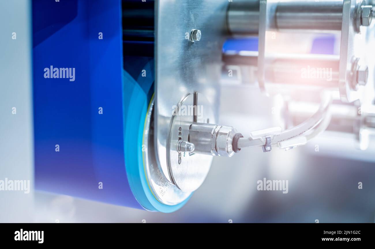 Selektiver Fokus auf Trommelmotor mit blauem Förderband. Elektromotor in der Lebensmittelfabrik. Rollenmotor aus Edelstahl. Lebensmitteltechnische Ausrüstung. Stockfoto