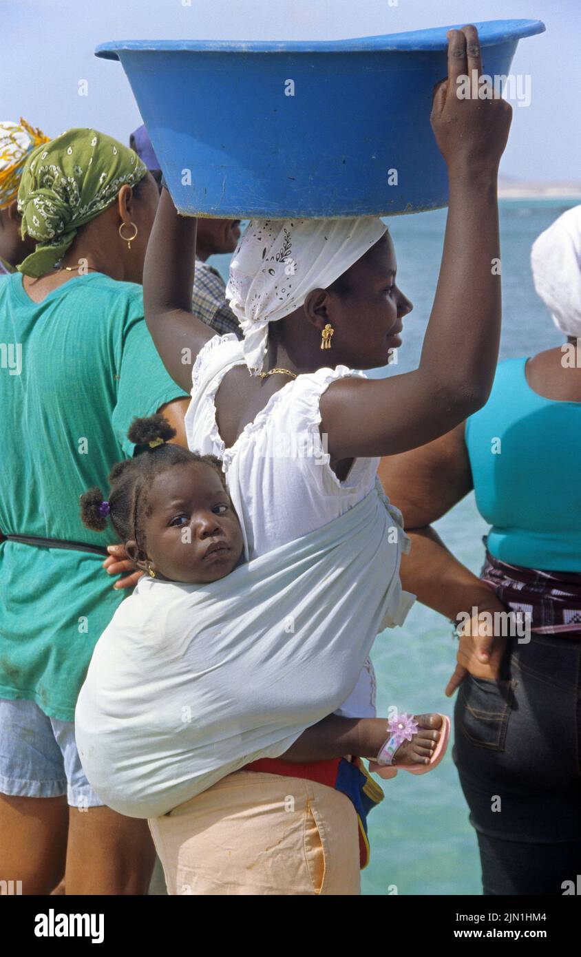 Die einheimische Frau, die ein Kind auf dem Rücken und eine Waschschüssel auf dem Kopf trägt, Sal Rei, Boavista, Kapverdische Inseln, Afrika Stockfoto