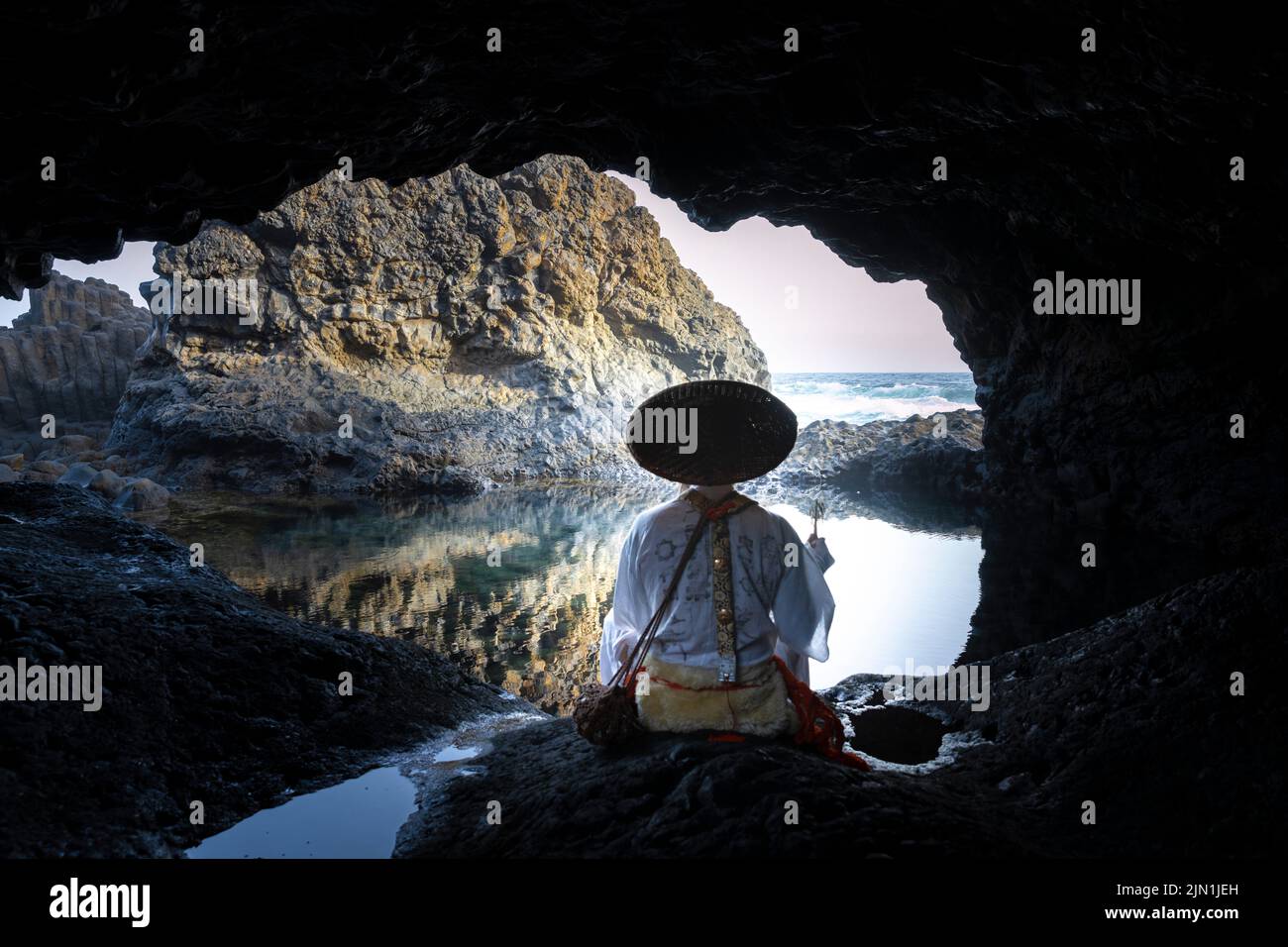 Der Mönch Shugendo sitzt in einer Höhle und meditiert, während er auf das offene Meer blickt Stockfoto