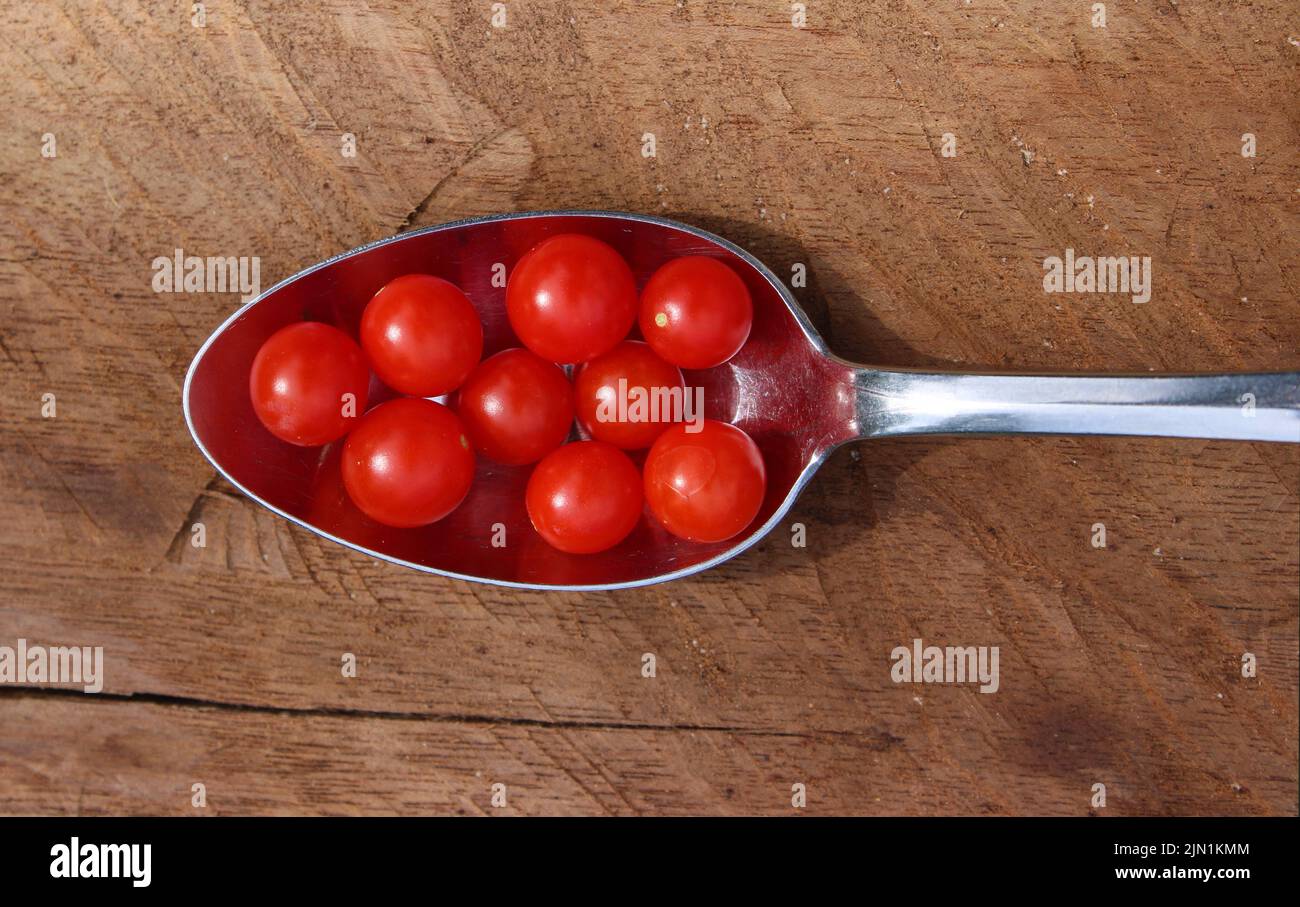 Eine Gruppe von winzigen Johannisbeeren-Tomaten auf einem Löffel Stockfoto
