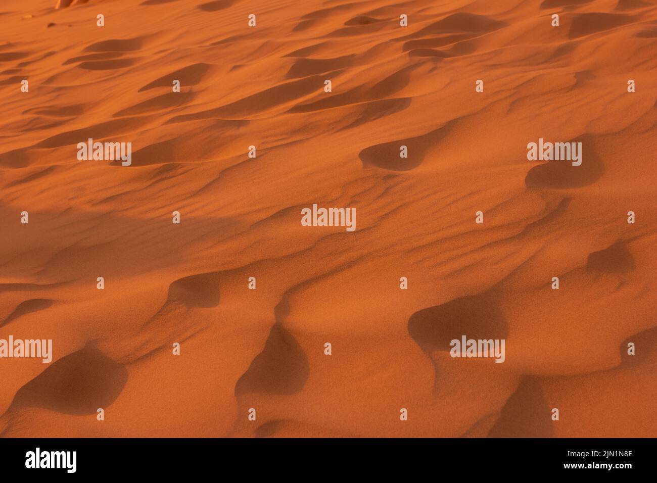 Muster aus Wüstensand, Textur, Hintergrund, orangefarbenes Sonnenuntergangslicht auf dem Sand Stockfoto