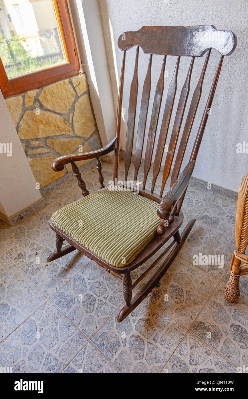 Hölzerner Schaukelstuhl auf der Terrasse mit gefliestem Boden Stockfoto