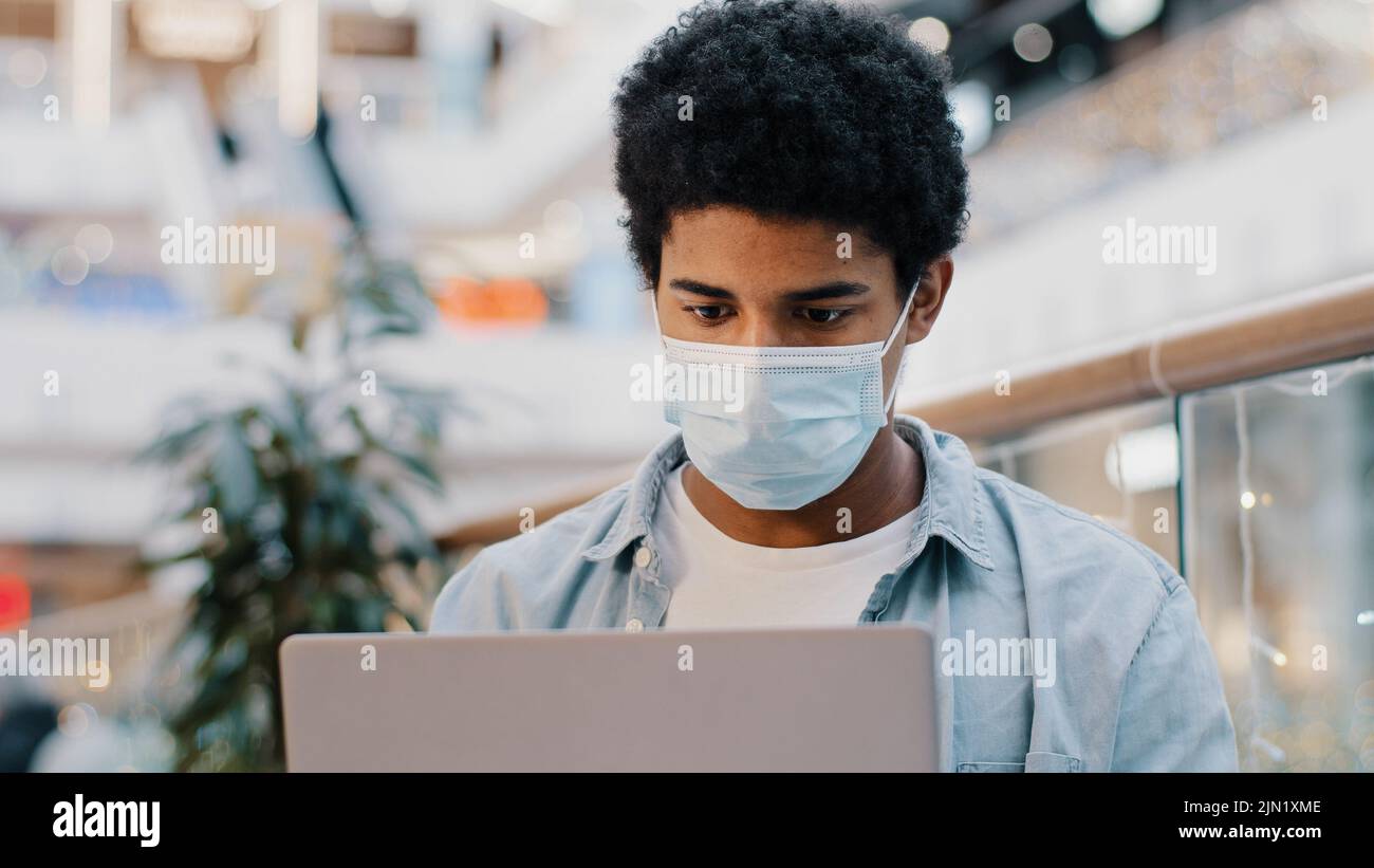 Portrait afroamerikanischer Kerl Student Benutzer Business man in medizinische Maske Denkplan schafft Idee Strategie arbeiten mit Laptop nachdenklich Nachdenken Stockfoto
