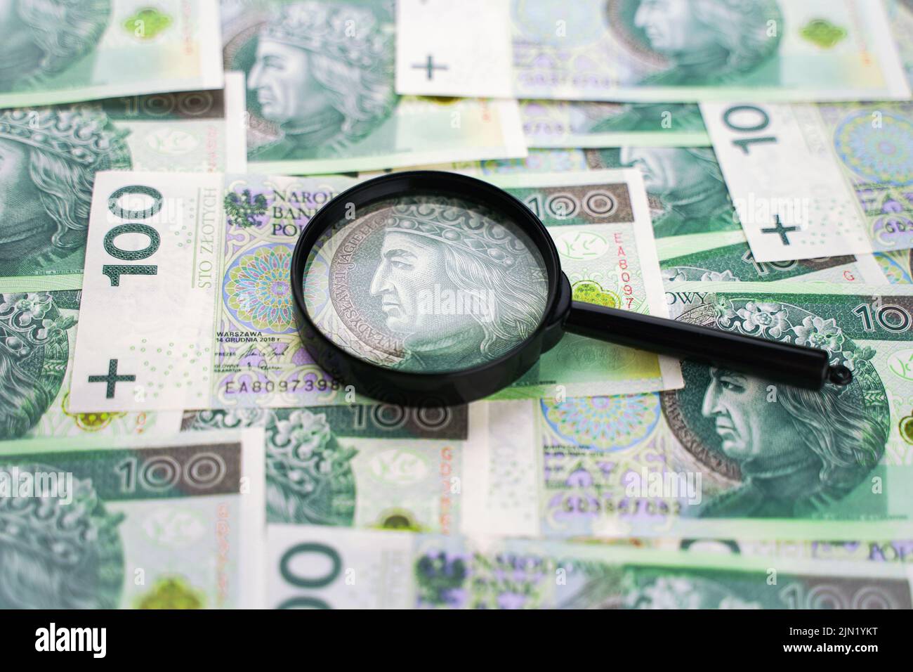Hintergrund aus dem Geld. Polnische Banknoten und Lupe. 100 Zloty Bargeld Stockfoto