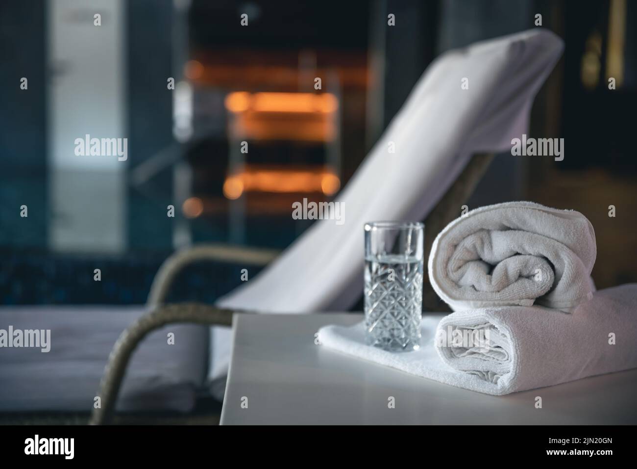 Spa-Hintergrund mit einem Glas Wasser und Handtüchern in einem Spa-Komplex. Stockfoto