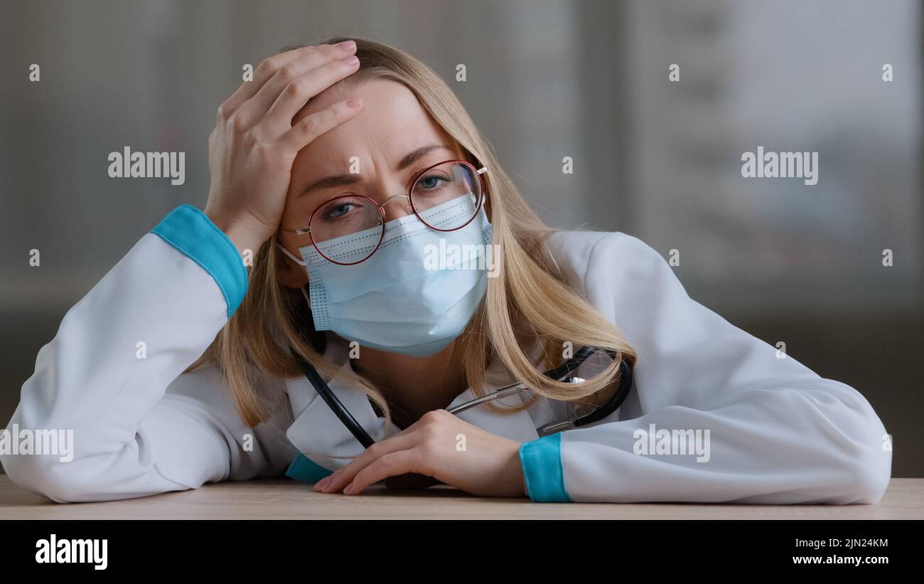 Verärgert traurig müde kaukasische Frau erschöpft überarbeiteten weiblichen Arzt Chirurg Arzt Krankenschwester Praktiker in schützende medizinische Gesichtsmaske Uniform Stockfoto