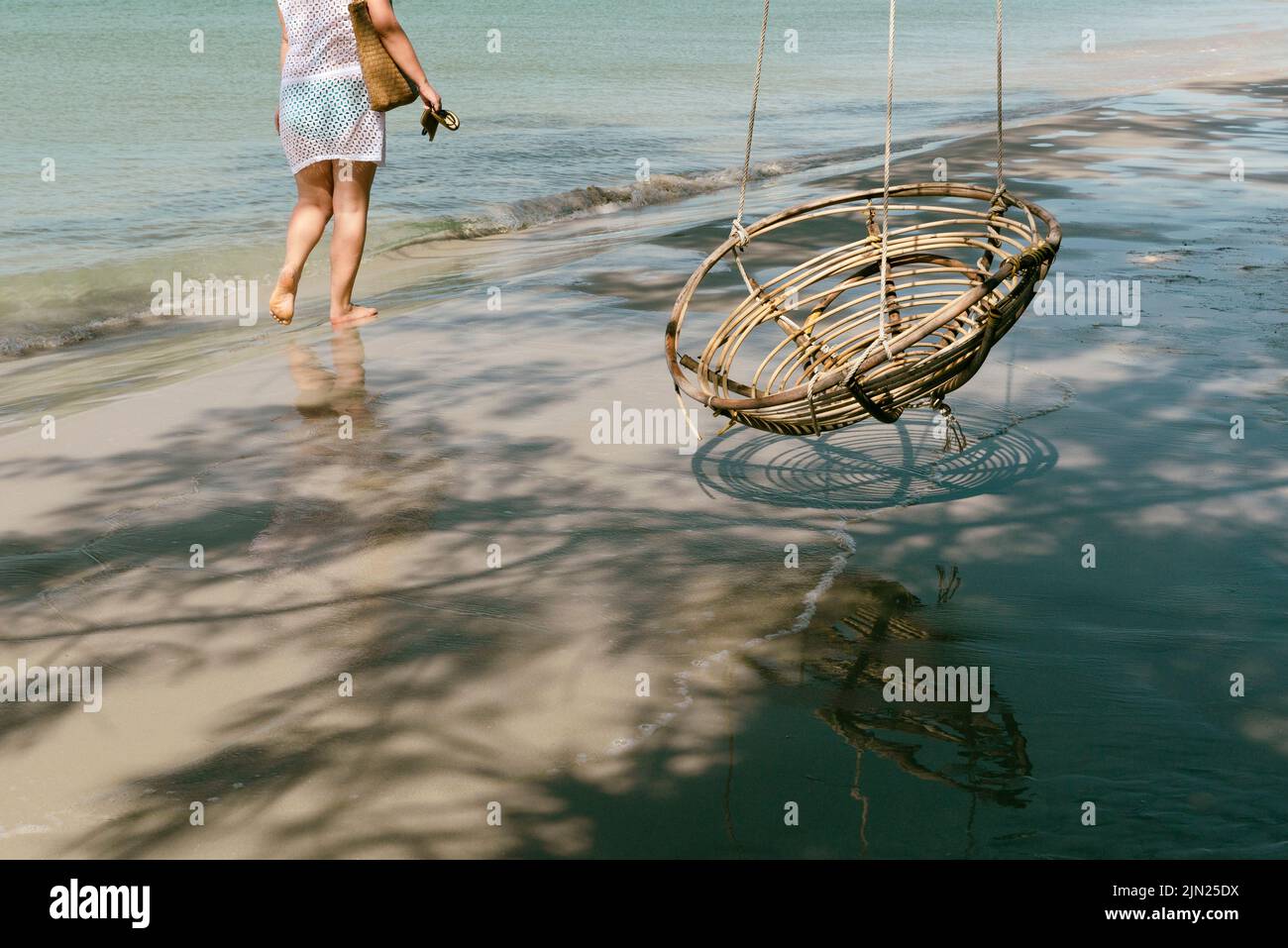 Frau, die am Strand mit einem Schaukelstuhl läuft Stockfoto