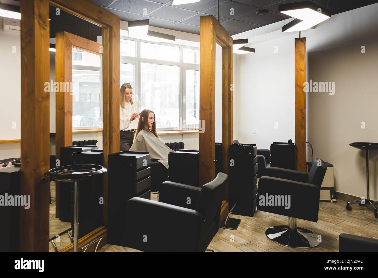 Der Friseur kämmt die Haare des Mädchens, indem er in einem Schönheitssalon stylt. Stockfoto
