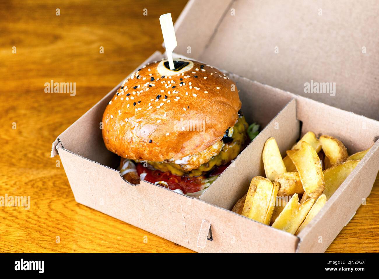Frische leckere Burger und pommes Frites in Papierkarton auf dem Tisch. Ungesunde Fast-Food-Hamburger. Stockfoto