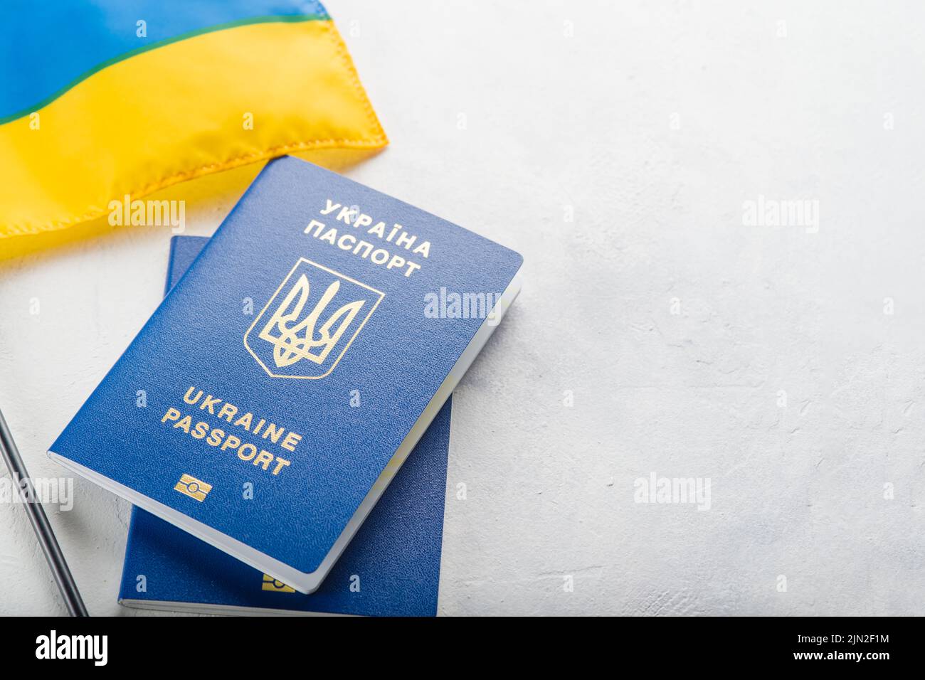 Auf weißem Hintergrund sind zwei biometrische ukrainische Pässe und eine kleine Flagge der Ukraine zu sehen. Patriotismus, Demokratie, Freiheit, Verfassung. Tourismus, Reisen Stockfoto