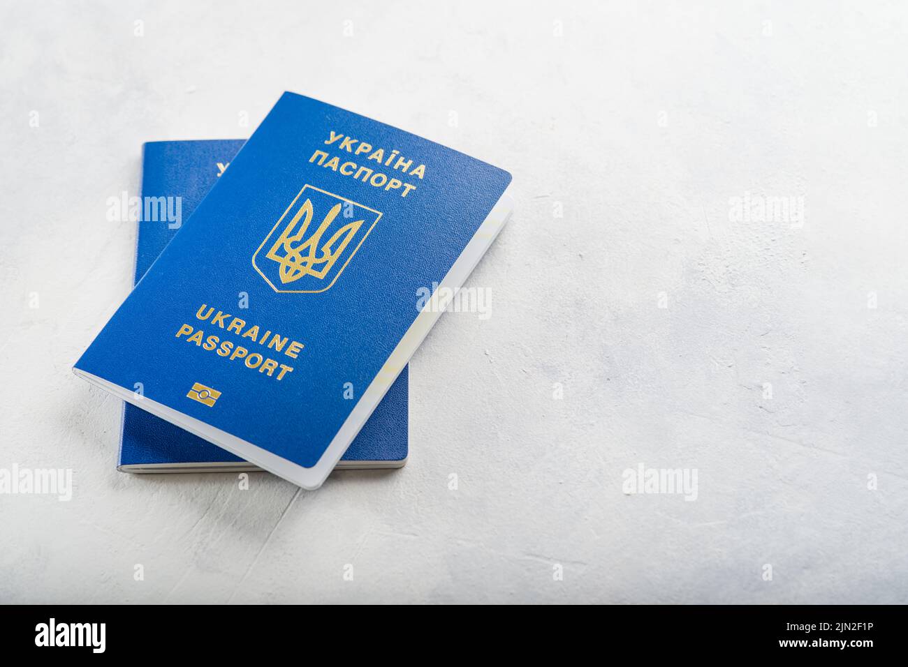 Zwei ukrainische Pässe auf weißem Hintergrund. Minimalismus. Auf dem Foto befinden sich keine Personen. Es ist freier Speicherplatz zum Einfügen vorhanden. Auswanderung, Geschäft, Reise Stockfoto