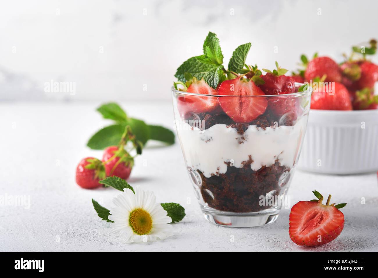 Kleinigkeiten. Brownies, frische Erdbeere und Mascarpone-Creme in Schichten auf Glas auf weißem Hintergrund gezackt. Portionsdesserts. Kein gebackener Brownie Cheesecak Stockfoto