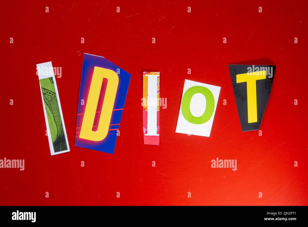 Das Wort „Idiot“ mit ausgeschnittenen Papierbuchstaben in der Lösegeld-Note-Effekt-Typografie Stockfoto