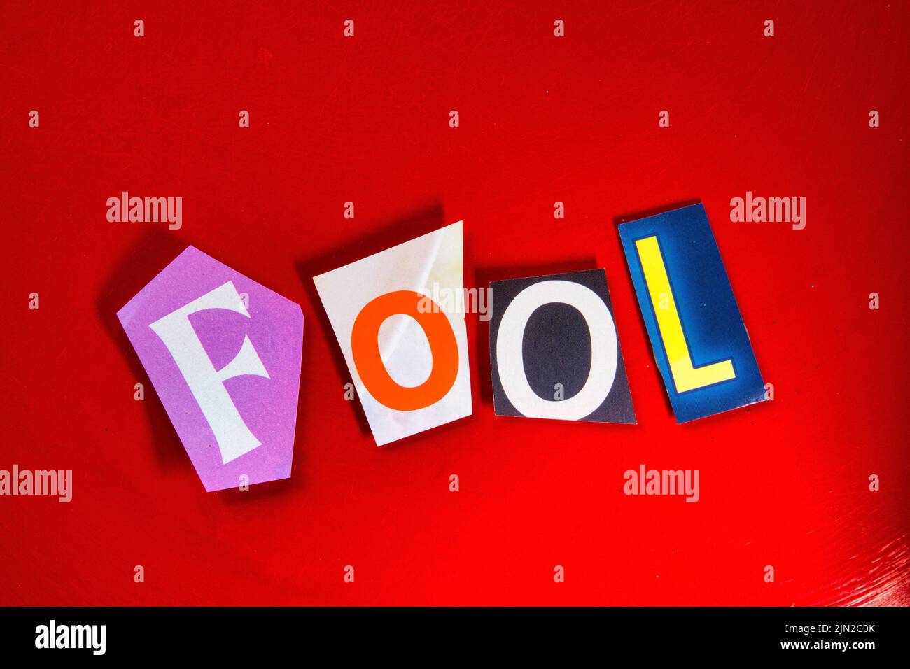 Das Wort „Fool“ mit ausgeschnittenen Papierbuchstaben in der Lösegeld-Note-Effekt-Typografie Stockfoto
