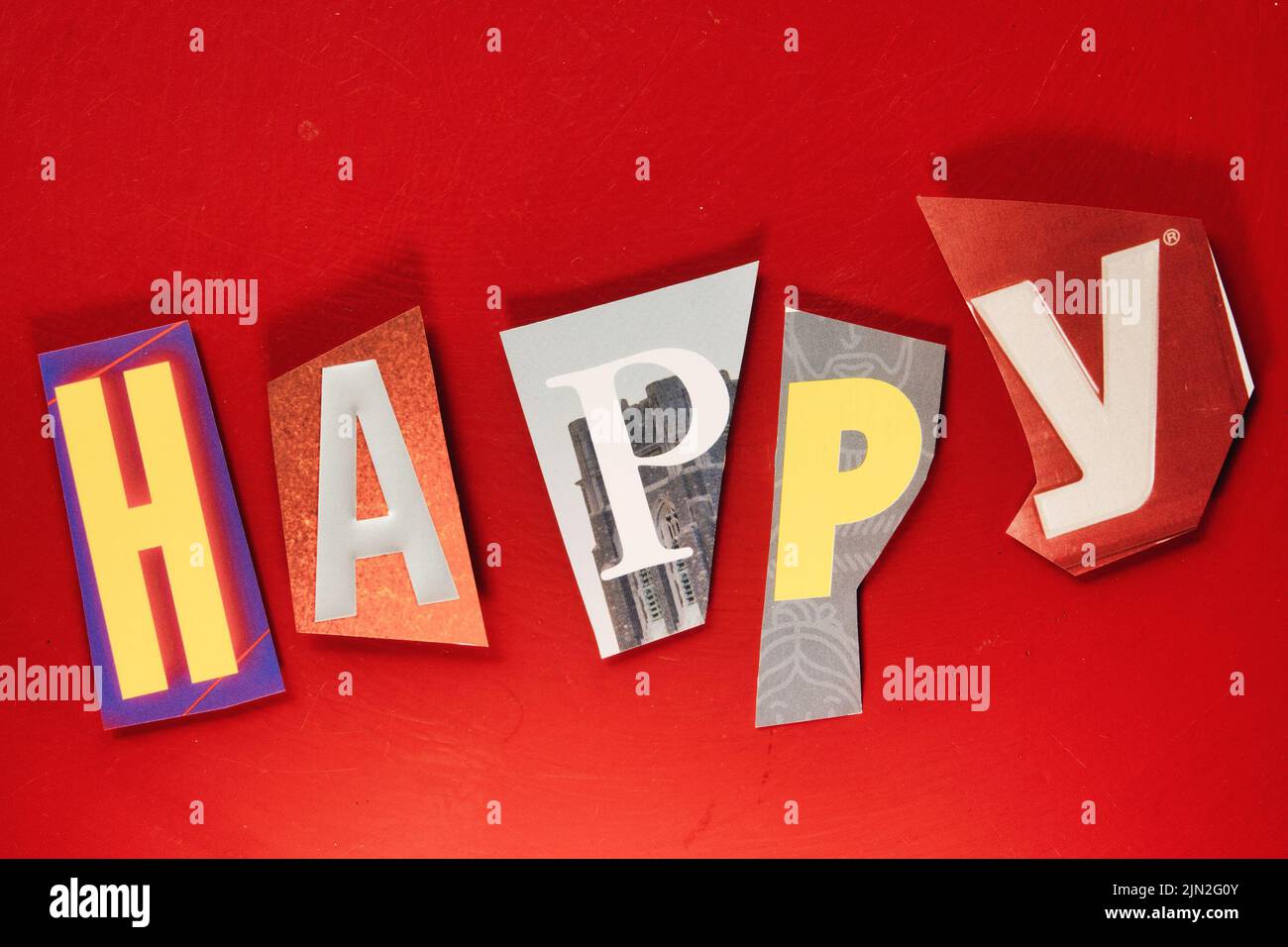 Das Wort „glücklich“ mit ausgeschnittenen Papierbuchstaben in der Lösegeld-Note-Effekt-Typografie Stockfoto