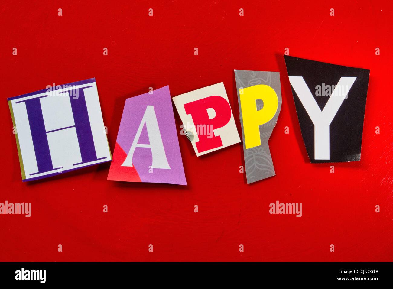 Das Wort „glücklich“ mit ausgeschnittenen Papierbuchstaben in der Lösegeld-Note-Effekt-Typografie Stockfoto