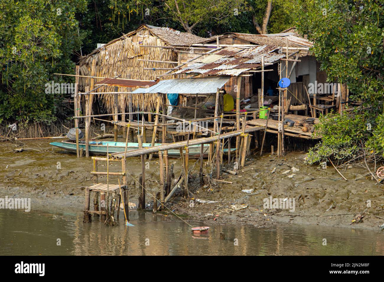 Ein einfaches Haus an einem schlammigen Flussufer. Stockfoto