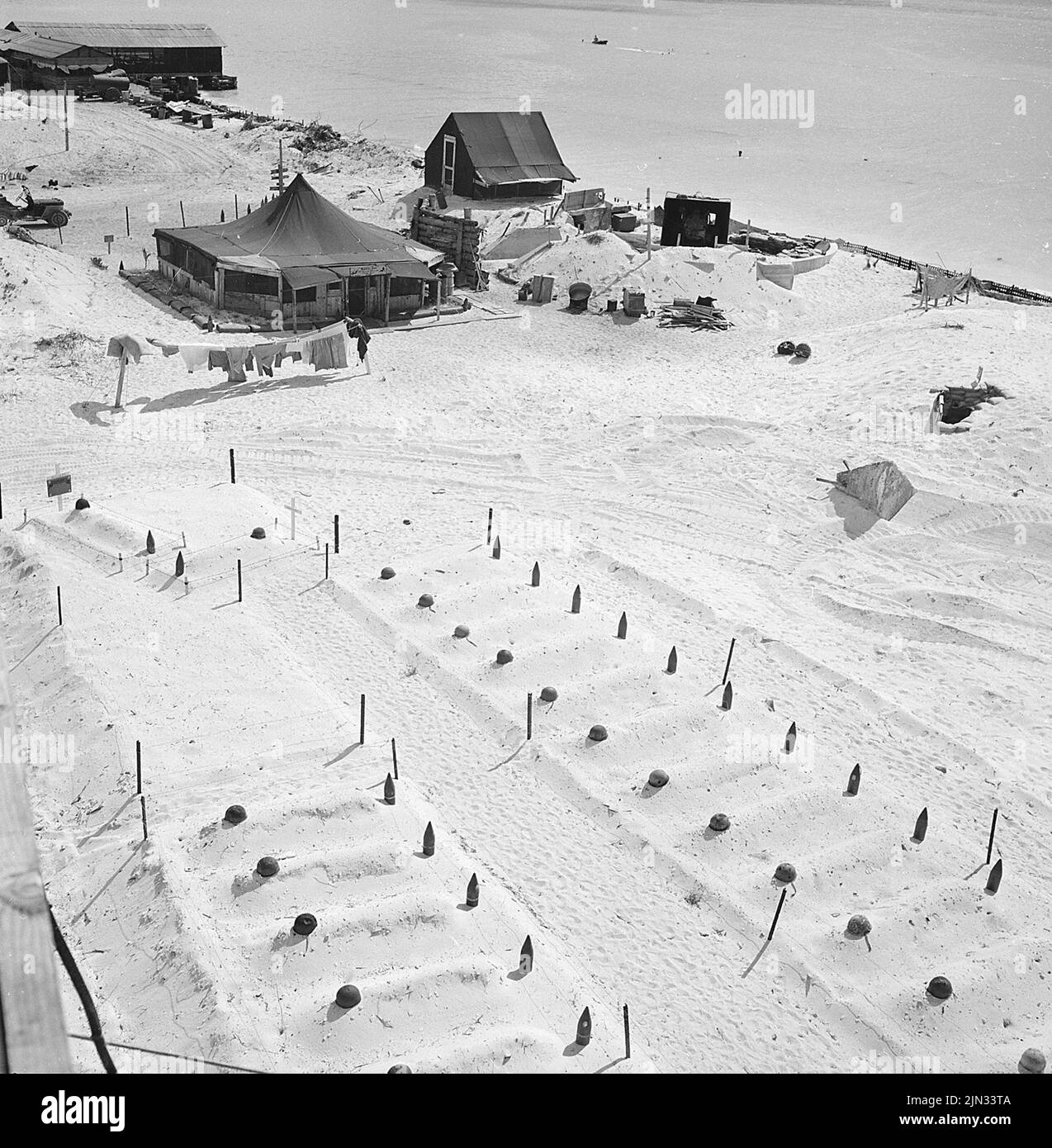 Leere Helme und ausgewendete Artilleriebranchen markieren die Gräber von Marineinfanatisten, die im März 1944 in Tarawa fielen. Die Landungen auf Tarawa waren Teil der US-Offensive gegen die Pazifikinseln, die Japan vor der Vorbereitung eines Angriffs auf das japanische Festland durchgeführt hatte. Stockfoto