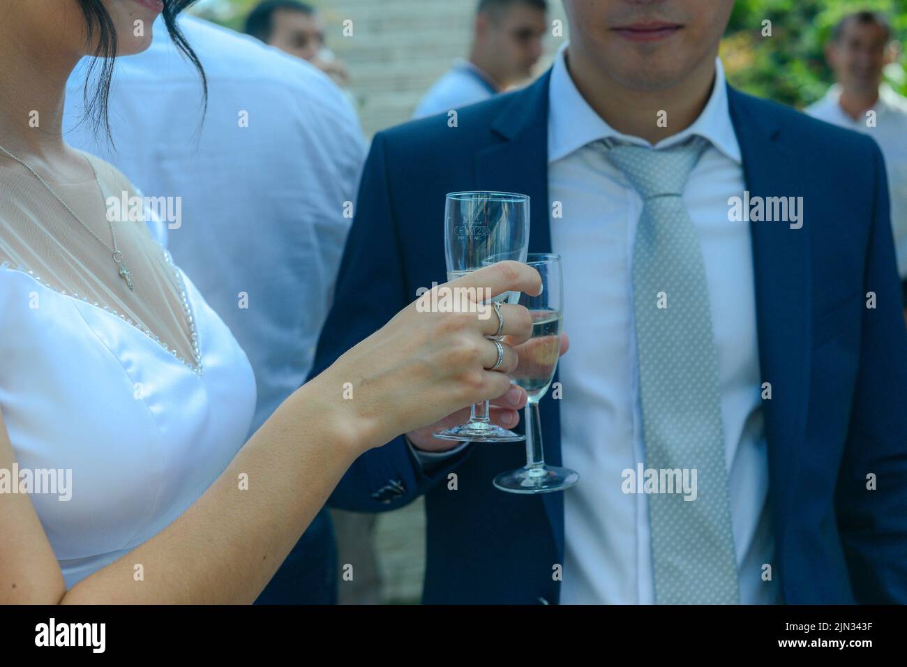 Junge Frau in einem weißen Hochzeitskleid mit einem Glas Champagner in der Hand Stockfoto