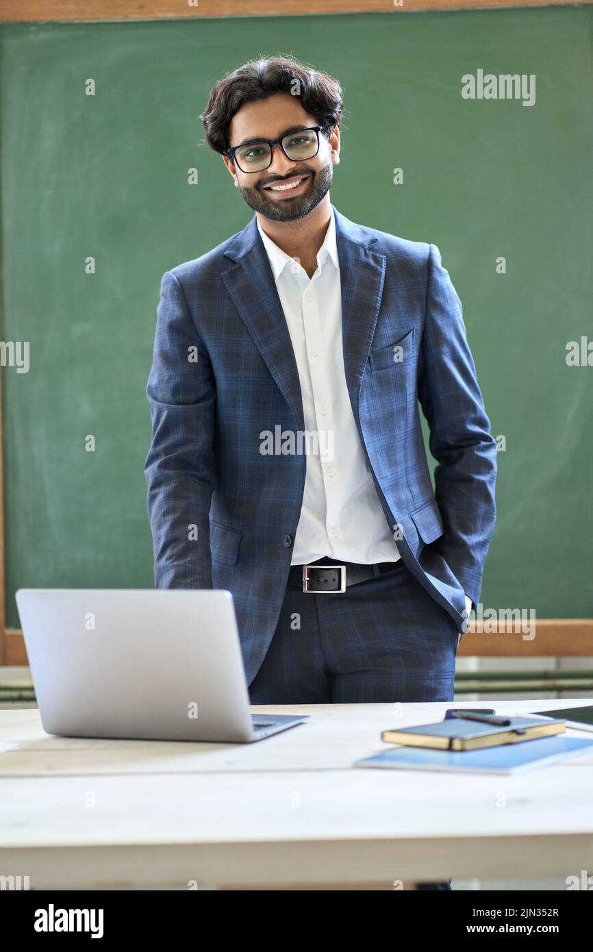 Lächelnder junger indischer Geschäftsmann in Anzug im Büro. Hochformat Stockfoto