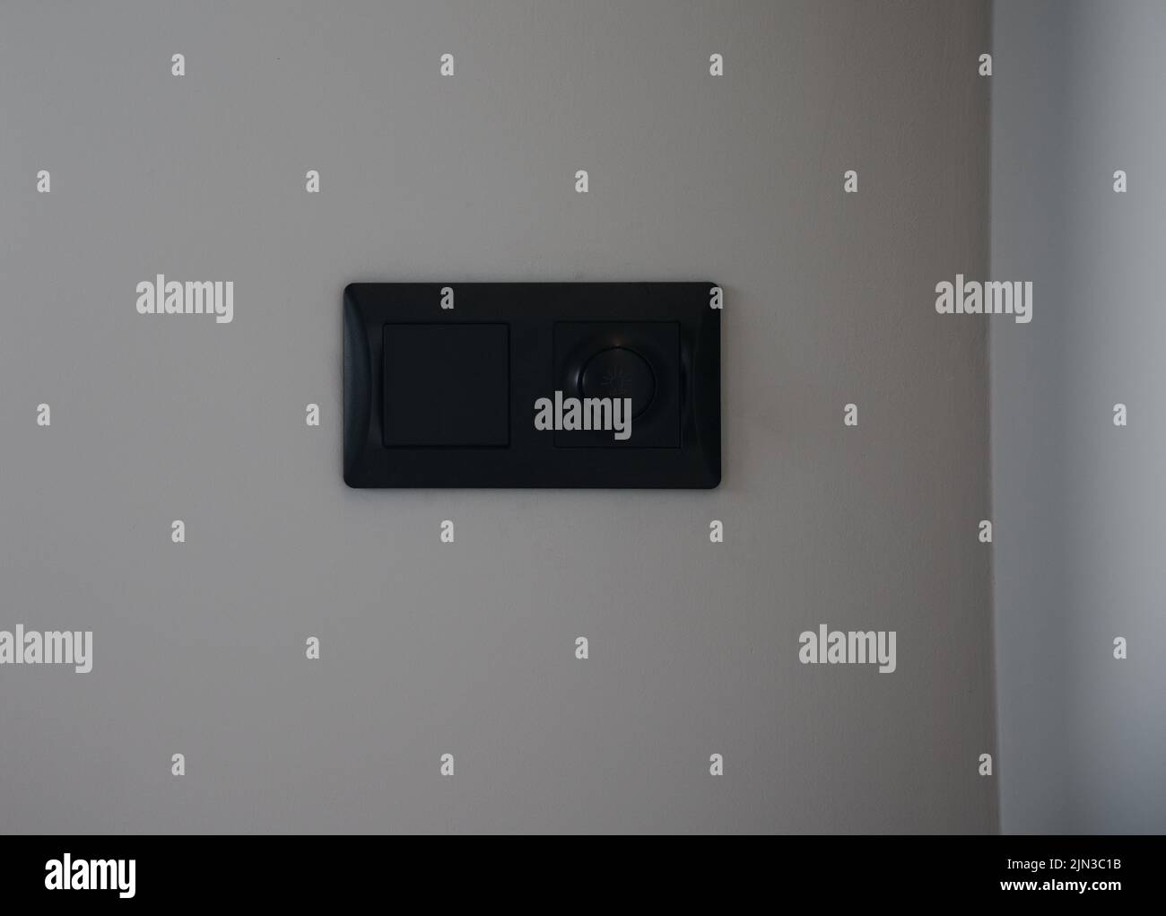 Moderner schwarzer Lichtschalter und Lichtdimmer an grauer Wand mit Kopierraum Stockfoto