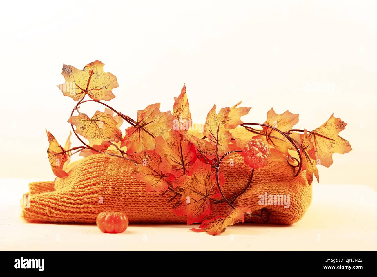 Herbstkomposition. Orangefarbener Strickpullover und Herbstblätter Stockfoto