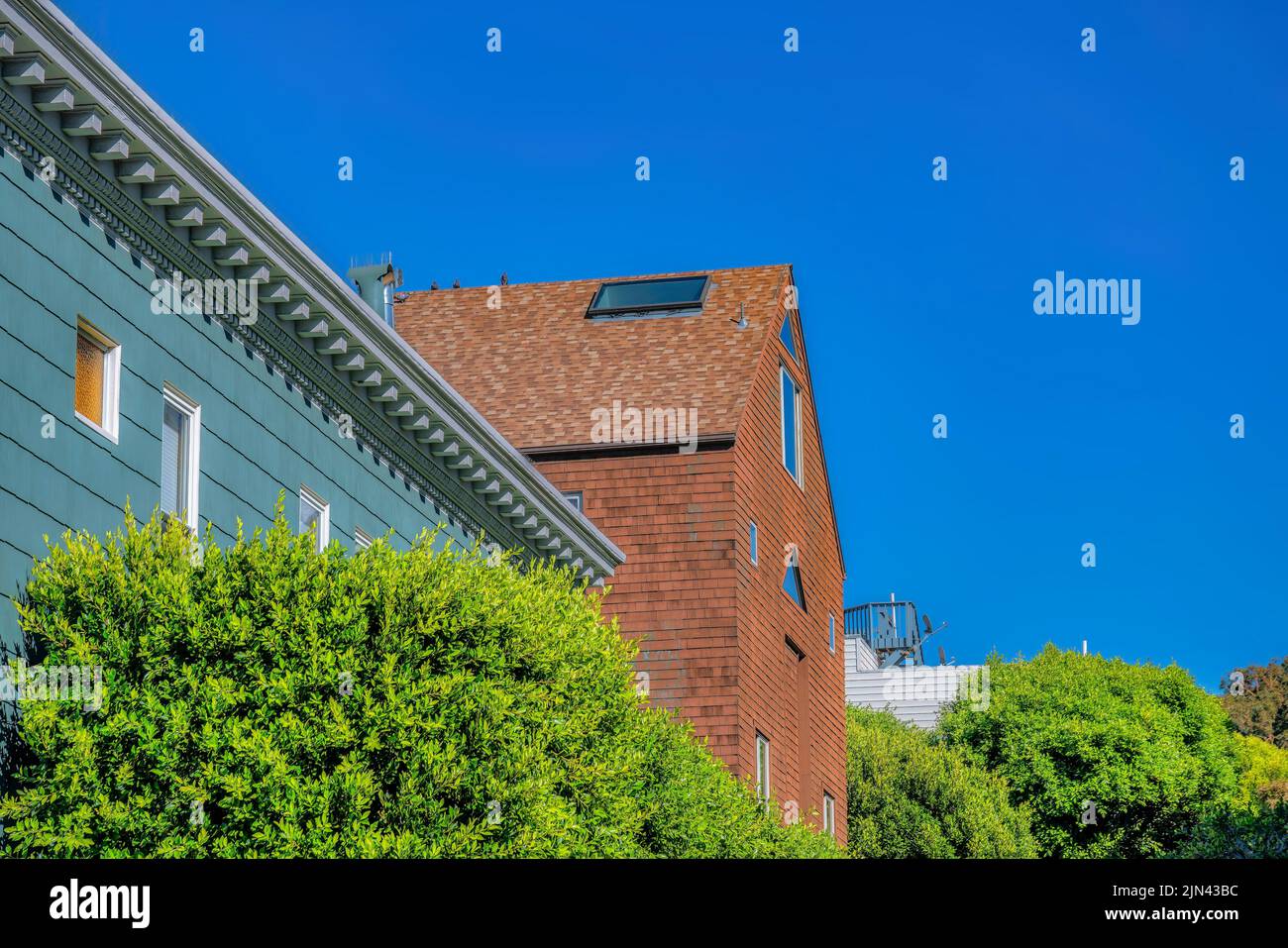 Seitenansicht von Häusern mit stilvollem Äußeren in San Francisco, CA. Es gibt ein Haus mit grau gesäumten Wänden und dekorativen Korbellen und Gebisszähnchen in der Nähe des Hou Stockfoto