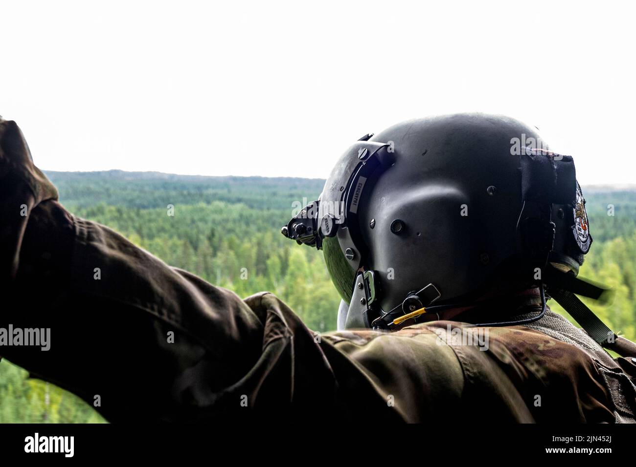 US Army Staff Sgt. Patrick Smith, ein Flugingenieur, der dem 1. Squadron, 214. General Support Aviation Bataillon, 12. Combat Aviation Brigade, zugewiesen wurde, schaut aus dem Fenster eines CH-47 Chinook Hubschraubers, der am 4. August 2022 in Tampere, Finnland, geflogen ist. Die 12. Combat Aviation Brigade ist eine der Einheiten, die die Strategie des U.S. European Command Theater unterstützen, indem sie das Engagement der USA für europäische Alliierte und Partner unter Beweis stellt und die Fähigkeiten der USA einem breiten Publikum vorstellt. 12 CAB ist unter anderem dem V Corps, dem amerikanischen Forward Deployed Corps in Europa, zugeordnet. Sie arbeiten mit den NATO-Alliierten an zusammen Stockfoto