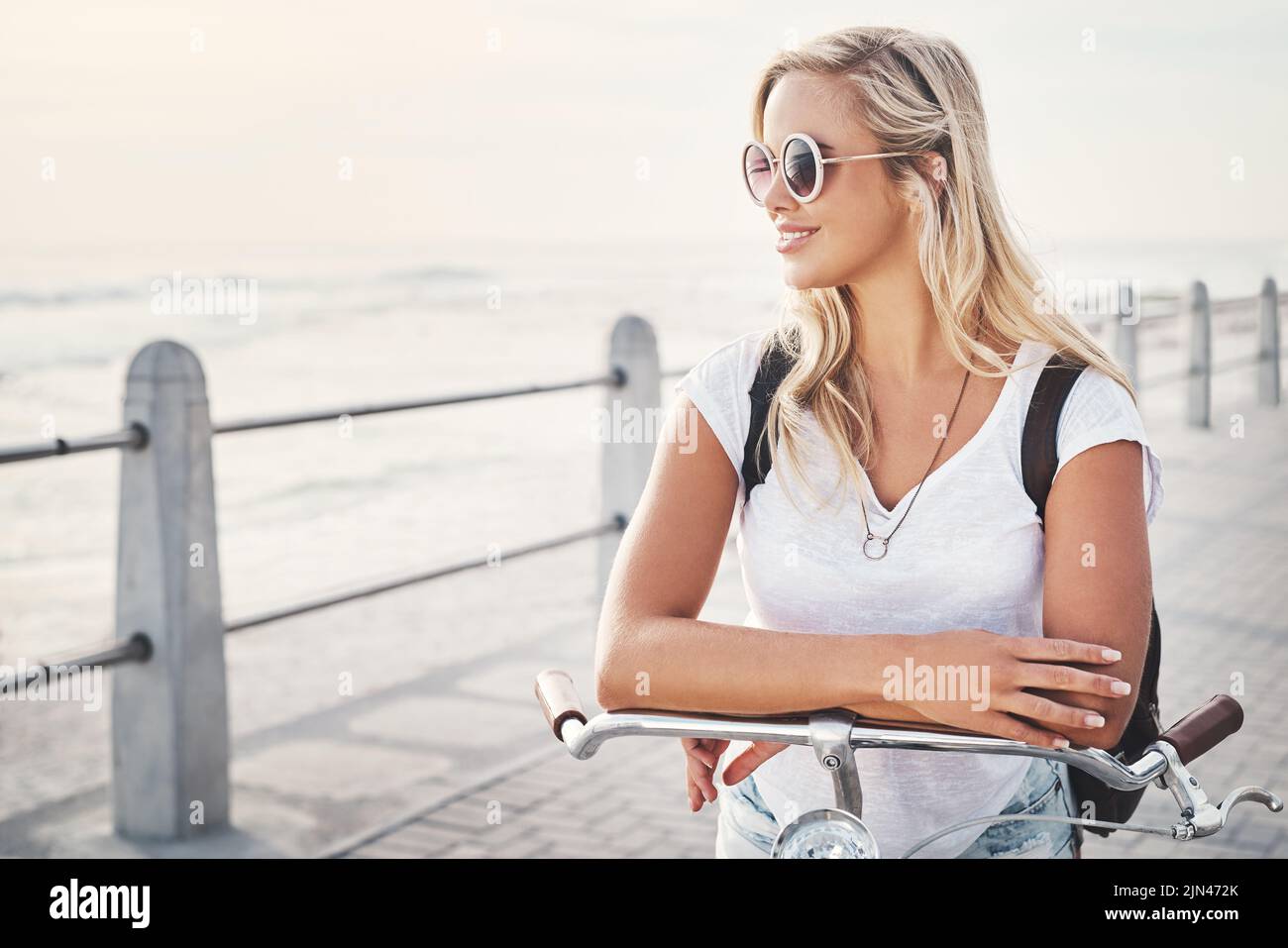 Diese Aussicht ist einfach perfekt. Eine schöne junge Frau auf der Promenade mit ihrem Fahrrad. Stockfoto