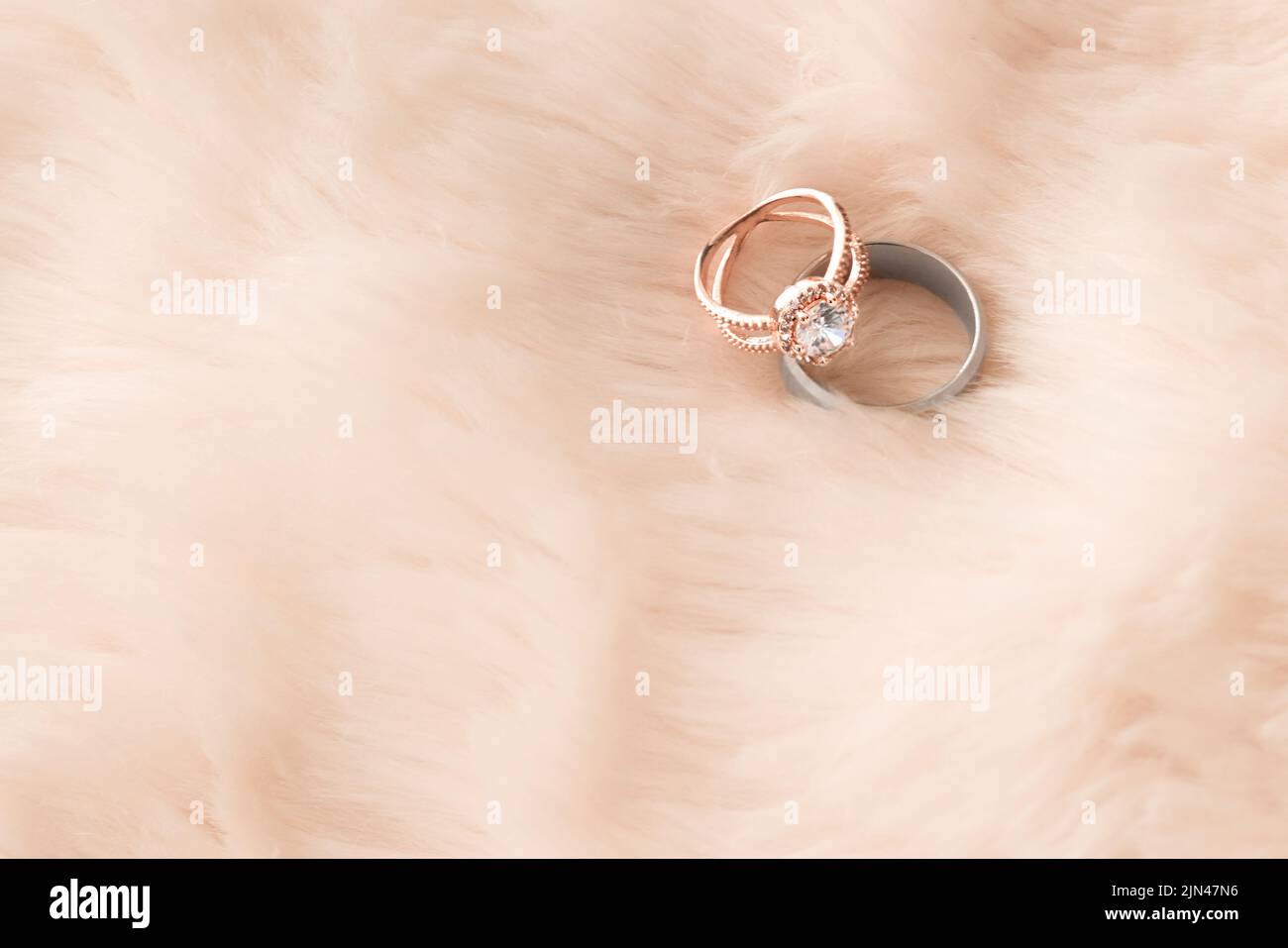 Zwei Leben, eine Liebe. Zwei Eheringe auf einem pelzigen Hintergrund. Stockfoto