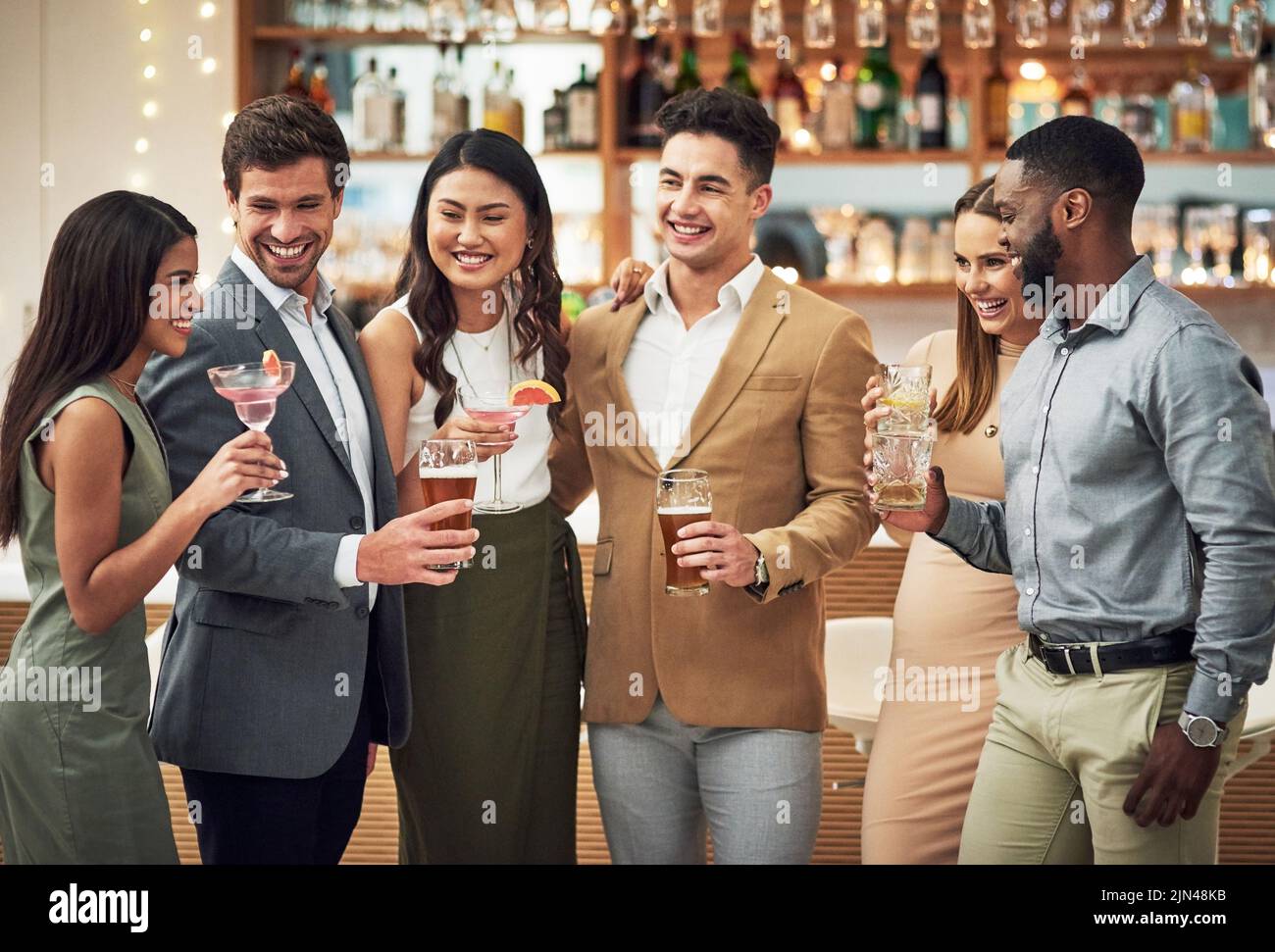 Wir müssen das öfter machen, eine Gruppe junger Freunde, die ihre Getränke halten, während sie in einer Bar stehen. Stockfoto