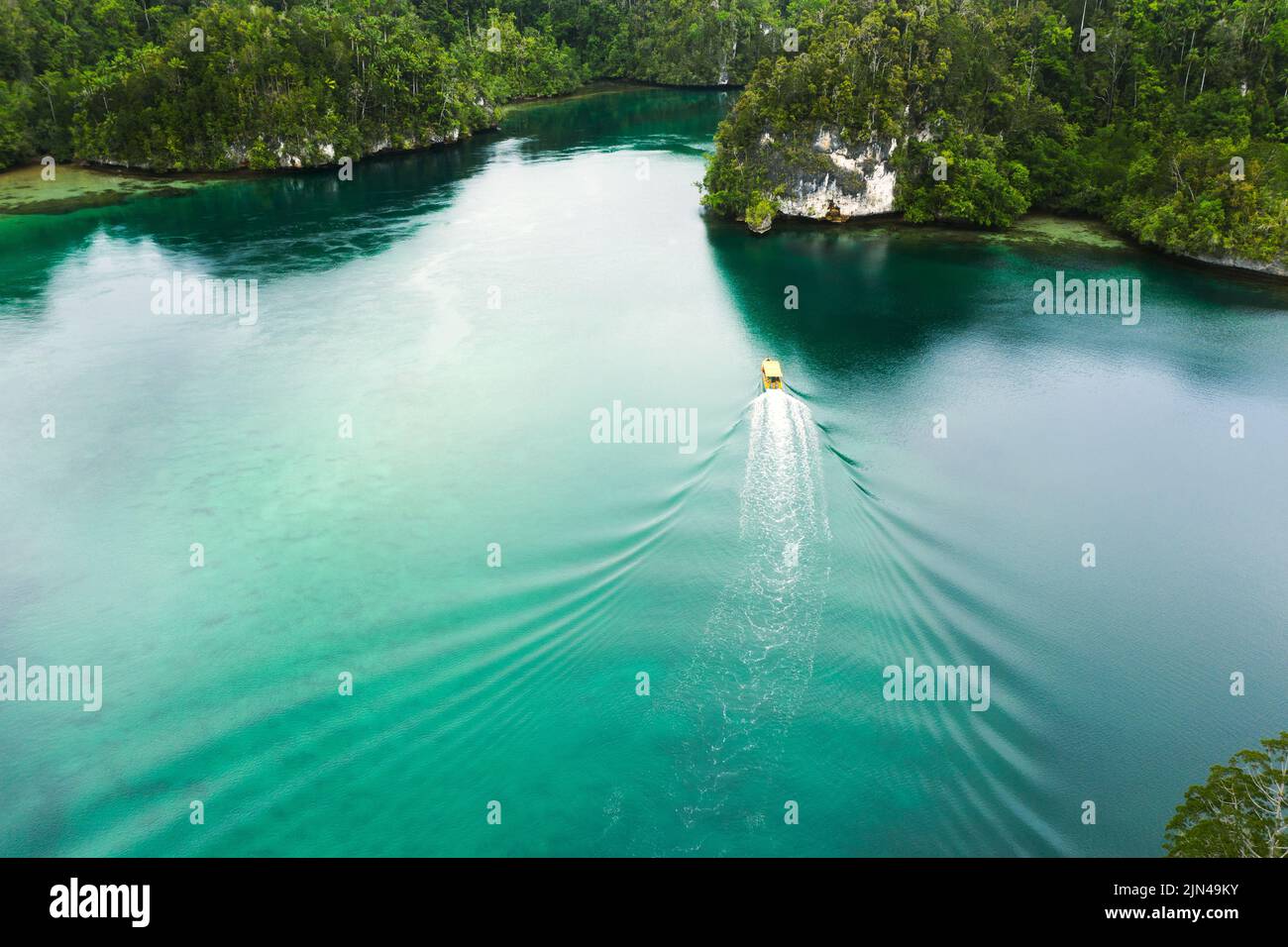 Lass das Abenteuer den Weg gehen. Aufnahme eines Bootes, das durch einen Kanal entlang der Raja Ampat-Inseln in Indonesien segelt. Stockfoto