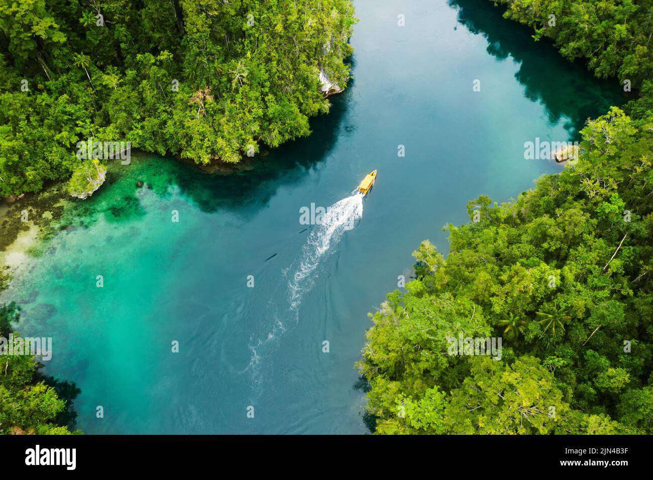 Setzen Sie die Segel und entdecken Sie neue Welten voller Abenteuer. Aufnahme eines Bootes, das durch einen Kanal entlang der Raja Ampat-Inseln in Indonesien segelt. Stockfoto