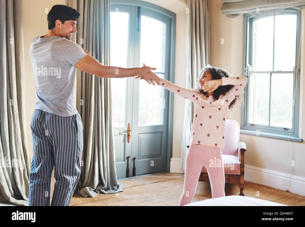 Ein Vater und seine kleine Tochter tanzen zu Hause zusammen. Stockfoto